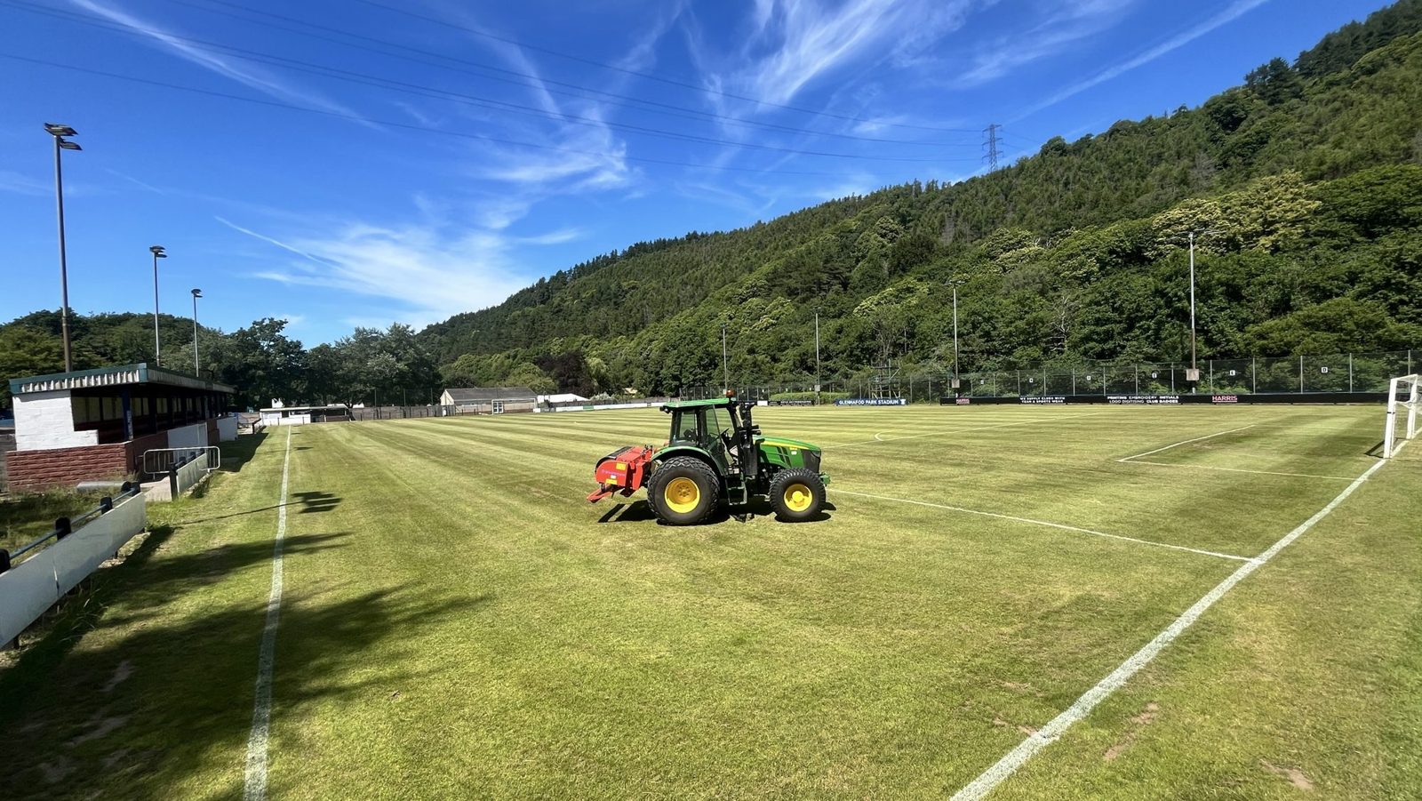 John Deere 5115M tractor with an aerator on the football pitch at Goytre FC